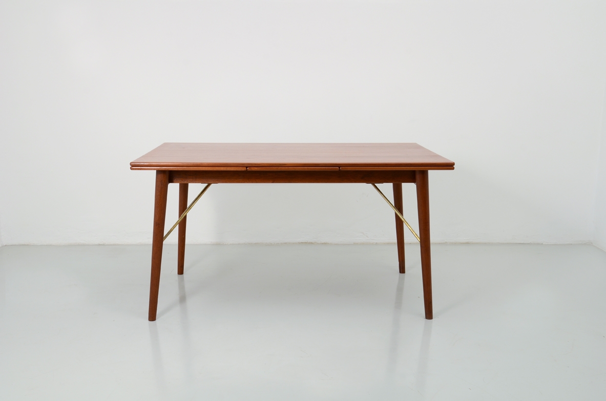Peter Hvdt & Orla Molgaard Nielsen, large 1960's extensible dining table in teak wood with four brass arms holding the legs.