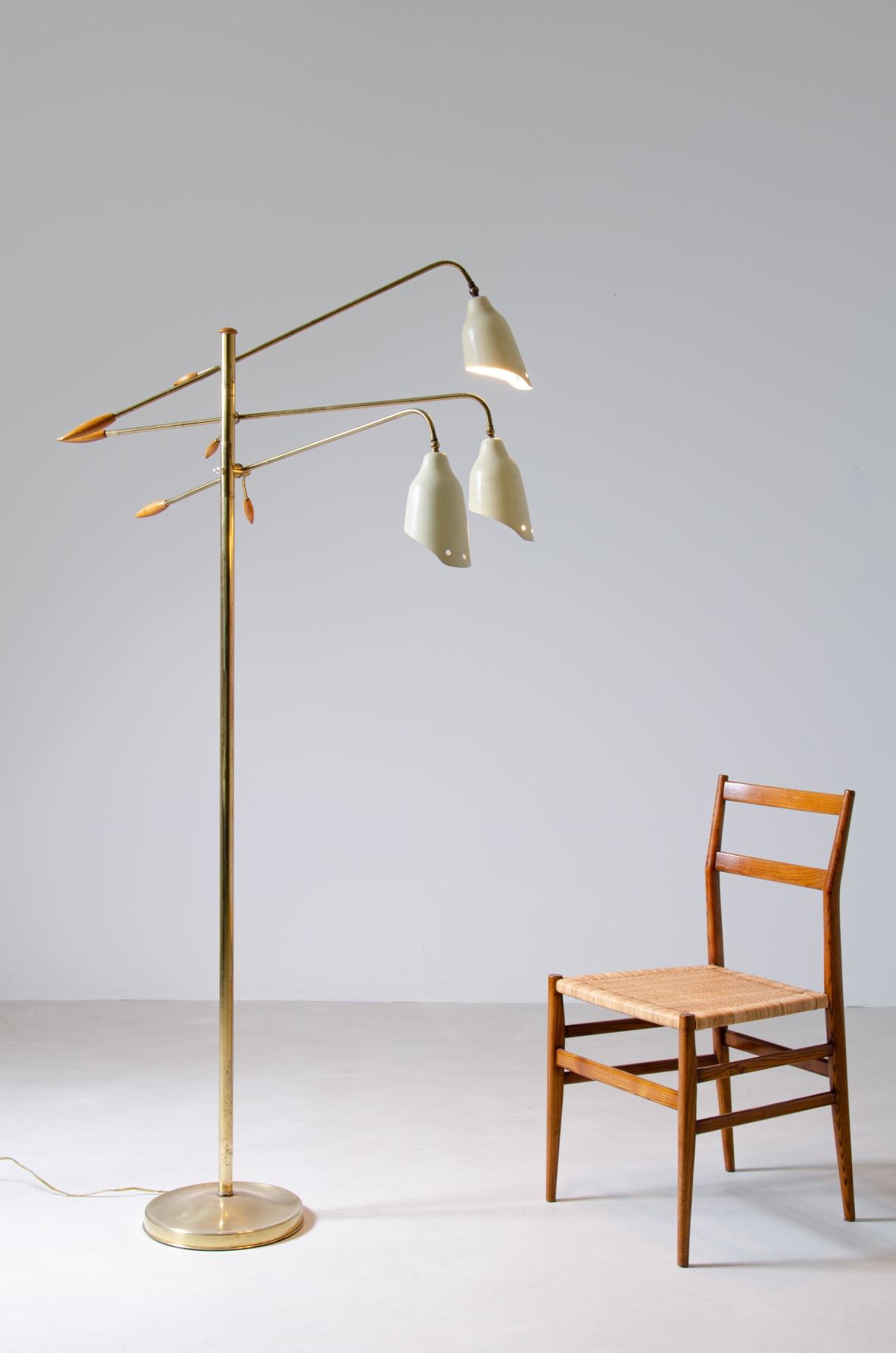 Piantana in ottone a tre bracci regolabili e coni sagomati in metallo verniciato con eleganti finali in legno tornito.  Prod. Arredoluce, 1950ca.