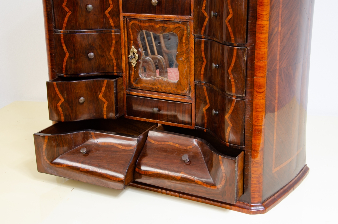 Ebanisteria genovese, 1750ca, monetiere in legno di viola filettato in legno di rosa con fronte mosso, edicola centrale con sportello sagomato e specchio centrale