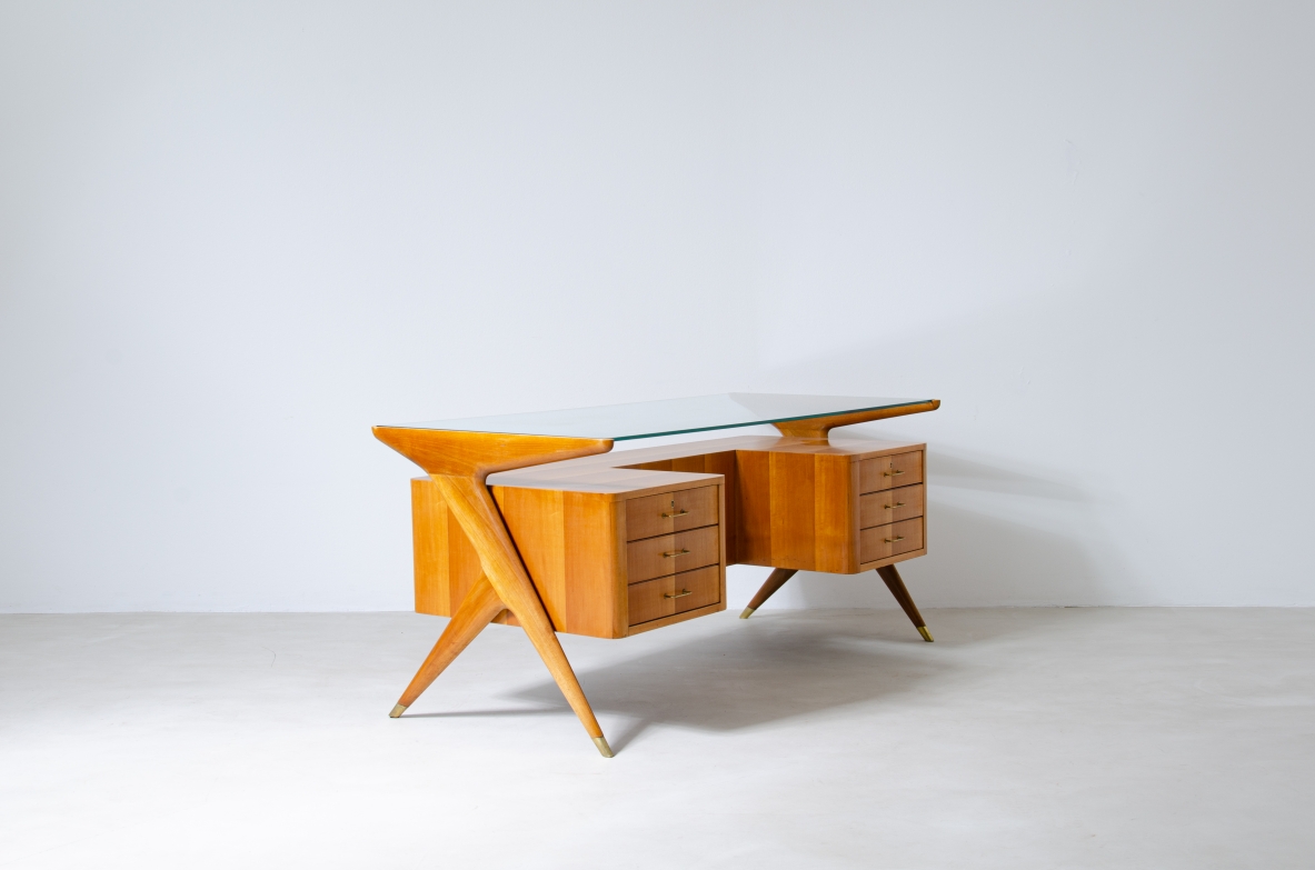 Writing table in blond wood with thick glass top and sculptural side uprights with brass tips.  1950's Italian manufacture.