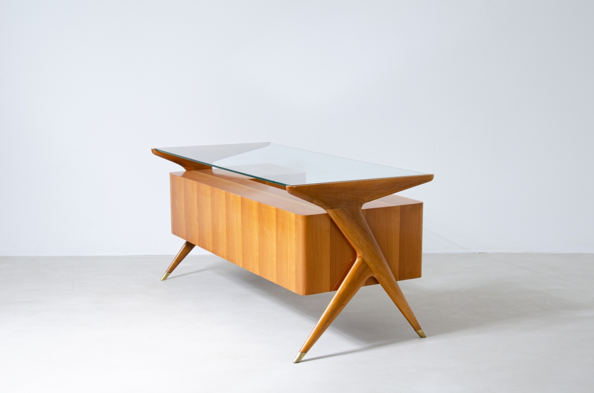 Writing table in blond wood with thick glass top and sculptural side uprights with brass tips.  1950's Italian manufacture.
