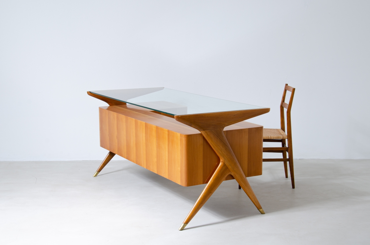 Writing table in blond wood with thick glass top and sculptural side uprights with brass tips.  1950's Italian manufacture.