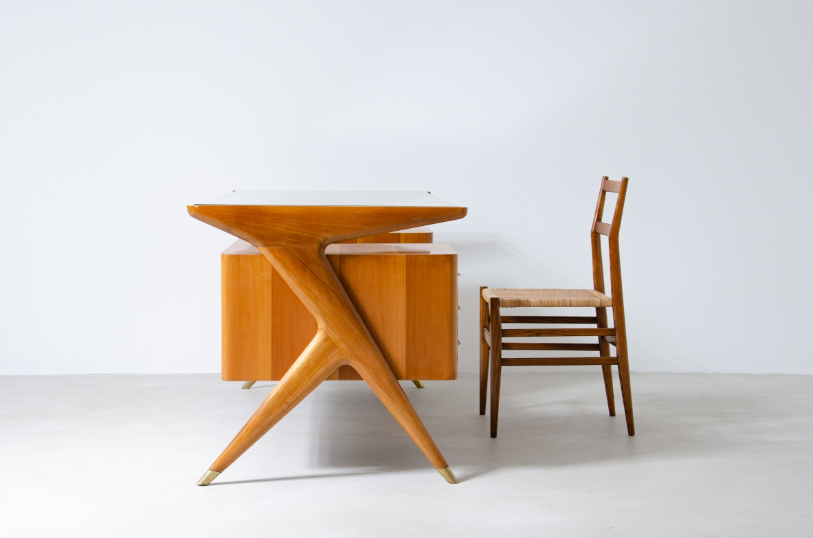 Writing table in blond wood with thick glass top and sculptural side uprights with brass tips.  1950's Italian manufacture.