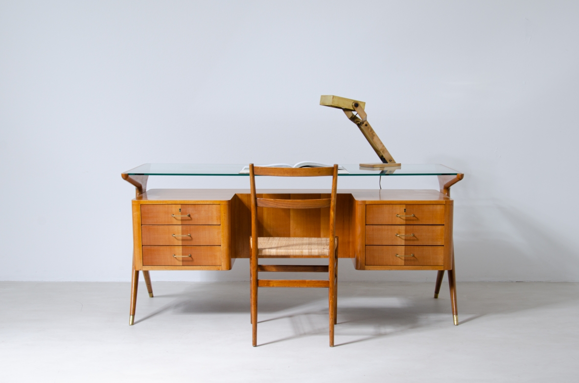 Writing table in blond wood with thick glass top and sculptural side uprights with brass tips.  1950's Italian manufacture.