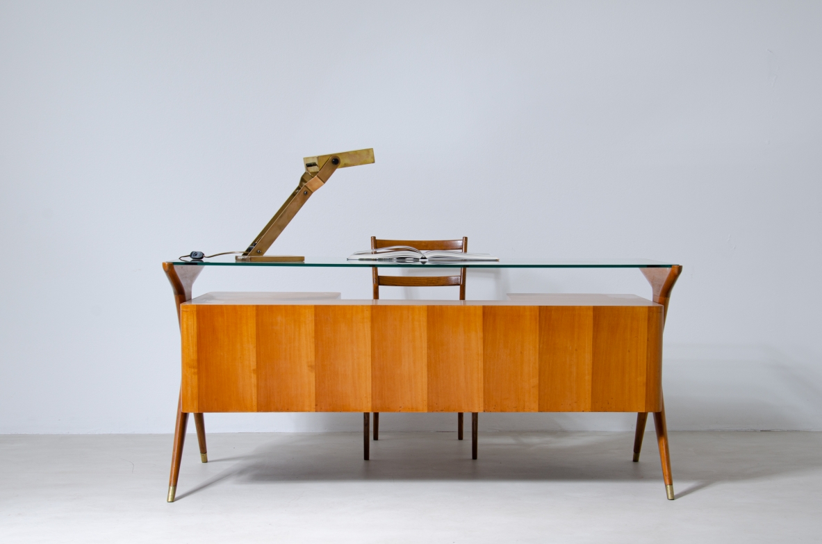 Writing table in blond wood with thick glass top and sculptural side uprights with brass tips.  1950's Italian manufacture.