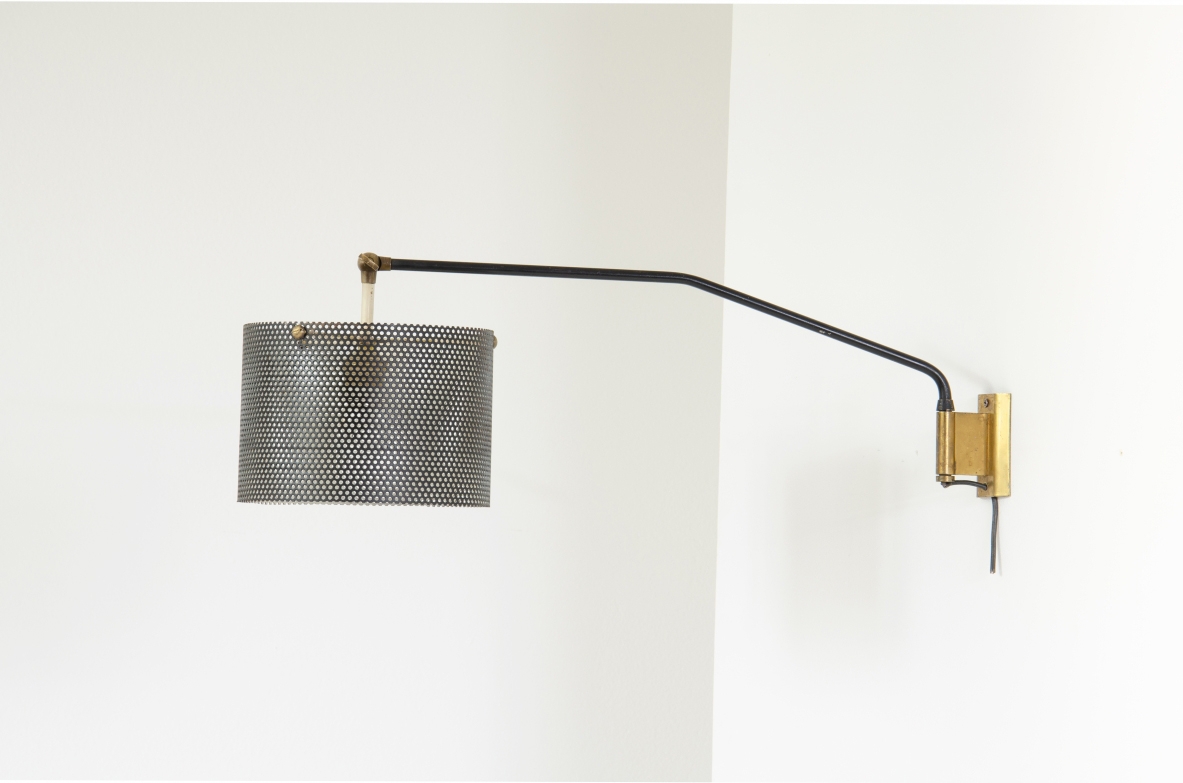 Stilnovo, lampada da parete con braccio tubolare e paralume in rete metallica. Dettagli in ottone. 1950ca.  Etichetta del produttore.