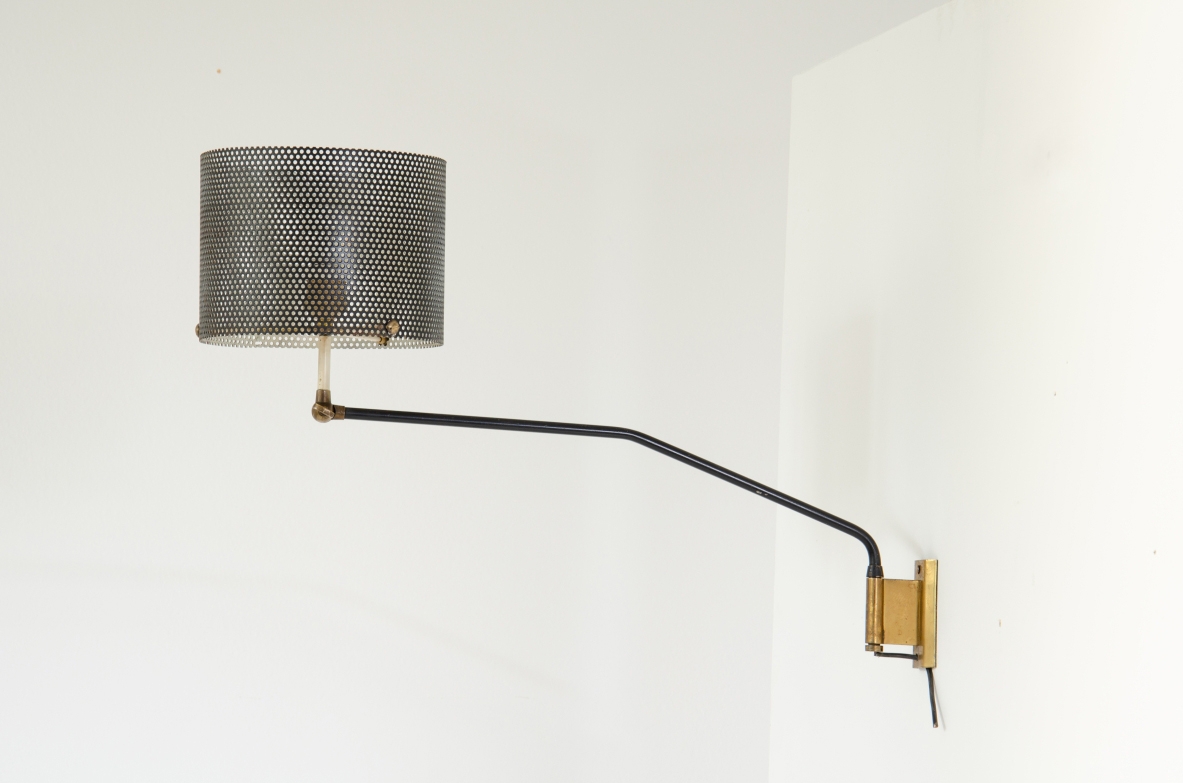 Stilnovo, lampada da parete con braccio tubolare e paralume in rete metallica. Dettagli in ottone. 1950ca.  Etichetta del produttore.