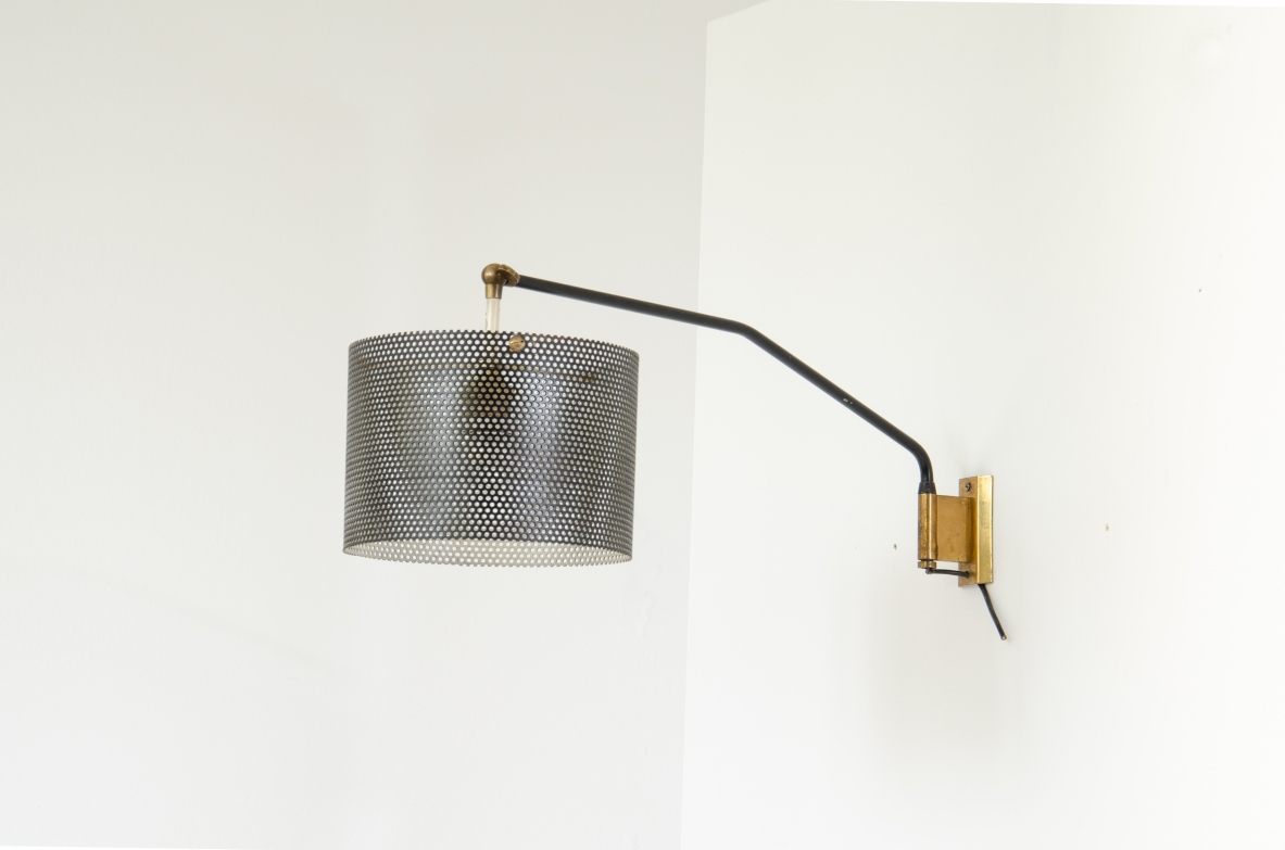 Stilnovo, lampada da parete con braccio tubolare e paralume in rete metallica. Dettagli in ottone. 1950ca.  Etichetta del produttore.