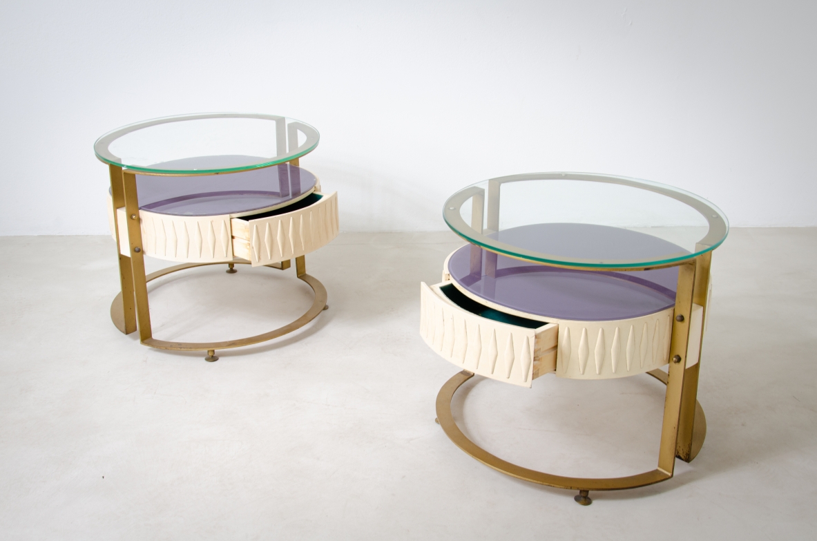 Coppia di comodini di forma ovale con struttura in metallo e legno laccato, doppio piano in vetro. Manifattura italiana, 1960ca.
