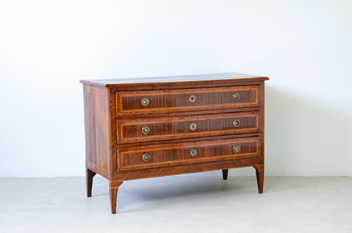 Mobile in legno lastronato in noce con filettature in legno di rosa, acero e ulivo. Tre cassetti con maniglie e bocchette in ottone.  Manifattura italiana, Lombardia epoca Luigi XVI, 1780ca.