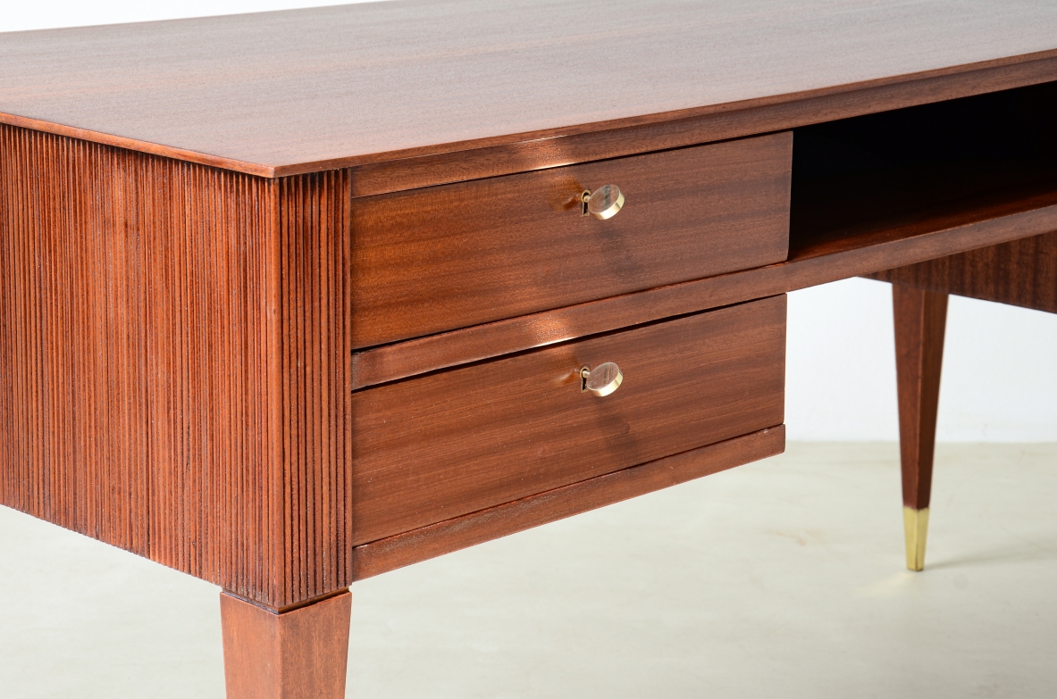 Scrivania in mogano a 4 cassetti con fronte e lati in legno grissinato,      gambe tronco piramidali con puntali in ottone.  Manifattura italiana anni 50'.