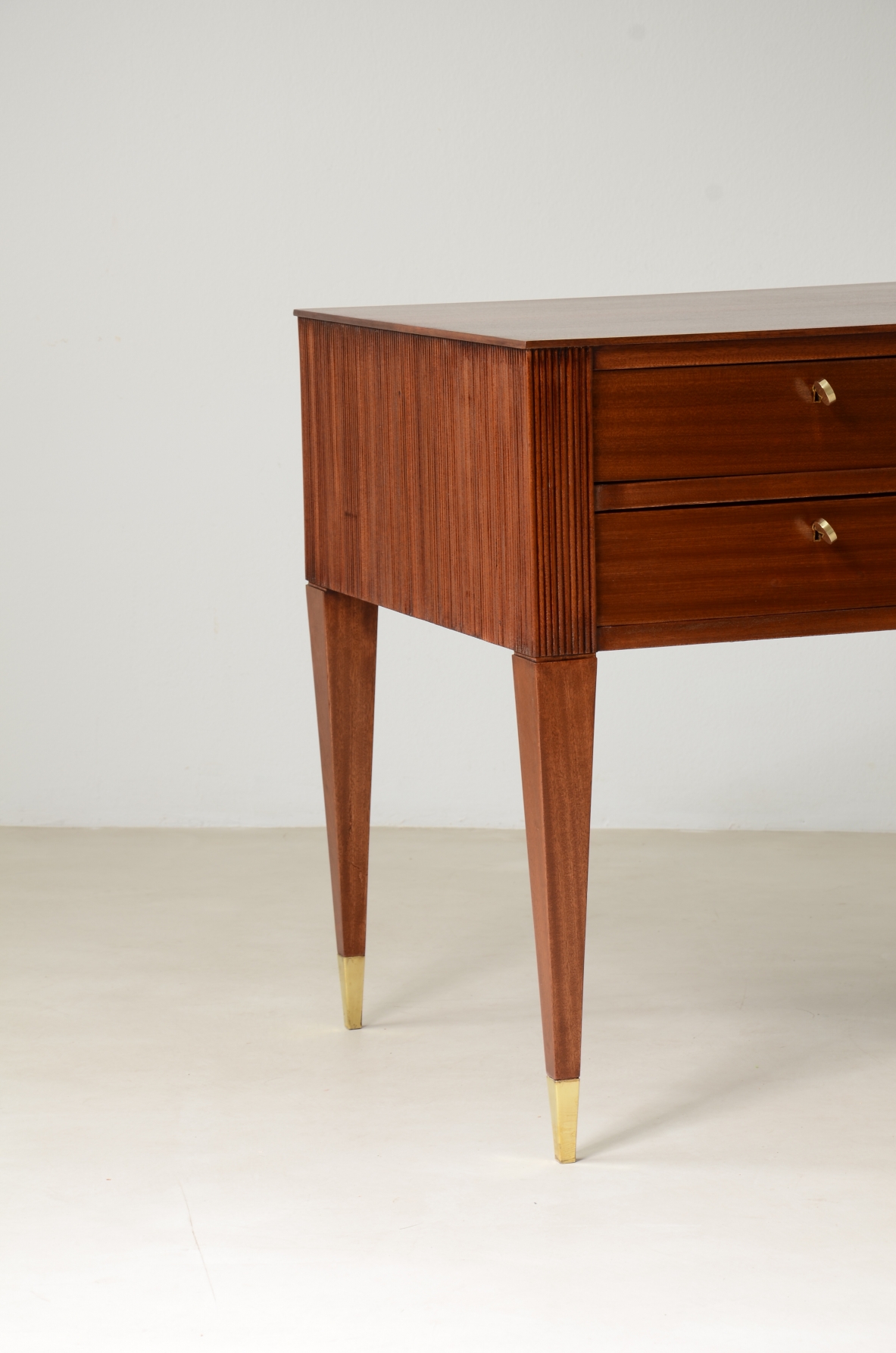 Scrivania in mogano a 4 cassetti con fronte e lati in legno grissinato,      gambe tronco piramidali con puntali in ottone.  Manifattura italiana anni 50'.