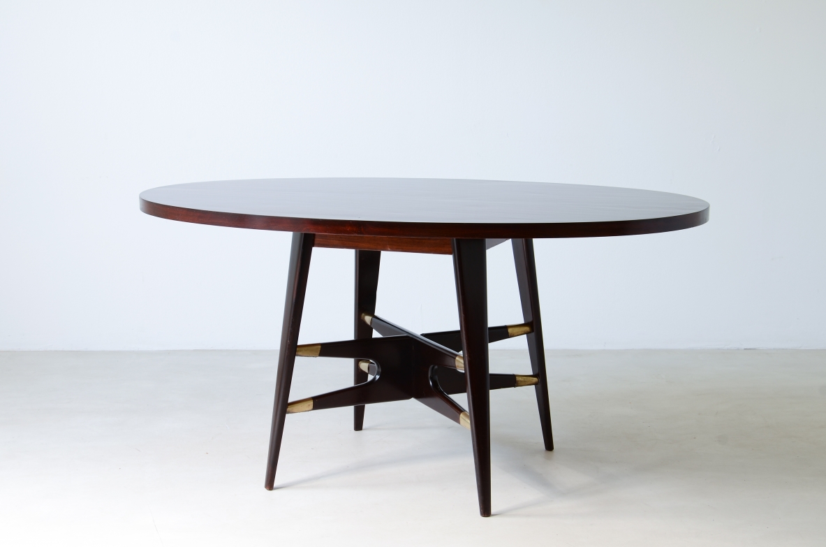Gianni Vigorelli  Elegant oval table in stained wood with four-legged uprights and important cross with brass tips.  Italian manufacture, attr. Vigorelli. 1950 approx.