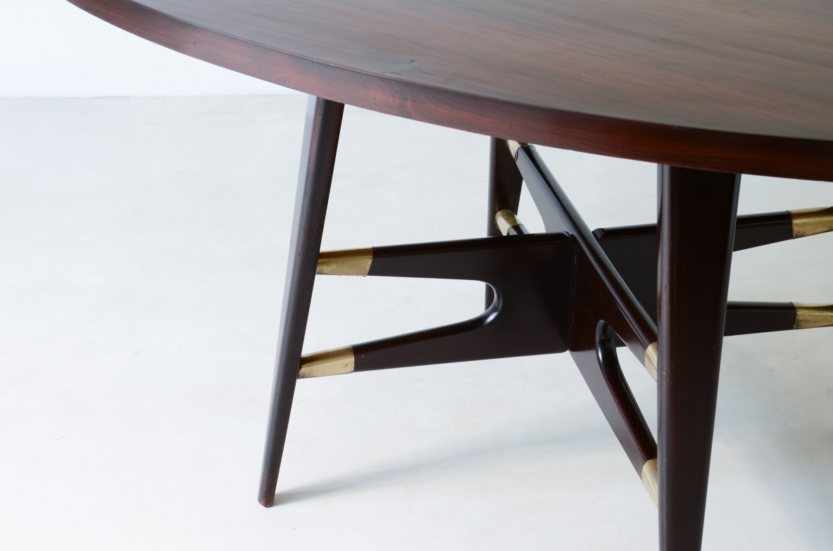 Gianni Vigorelli  Elegant oval table in stained wood with four-legged uprights and important cross with brass tips.  Italian manufacture, attr. Vigorelli. 1950 approx.