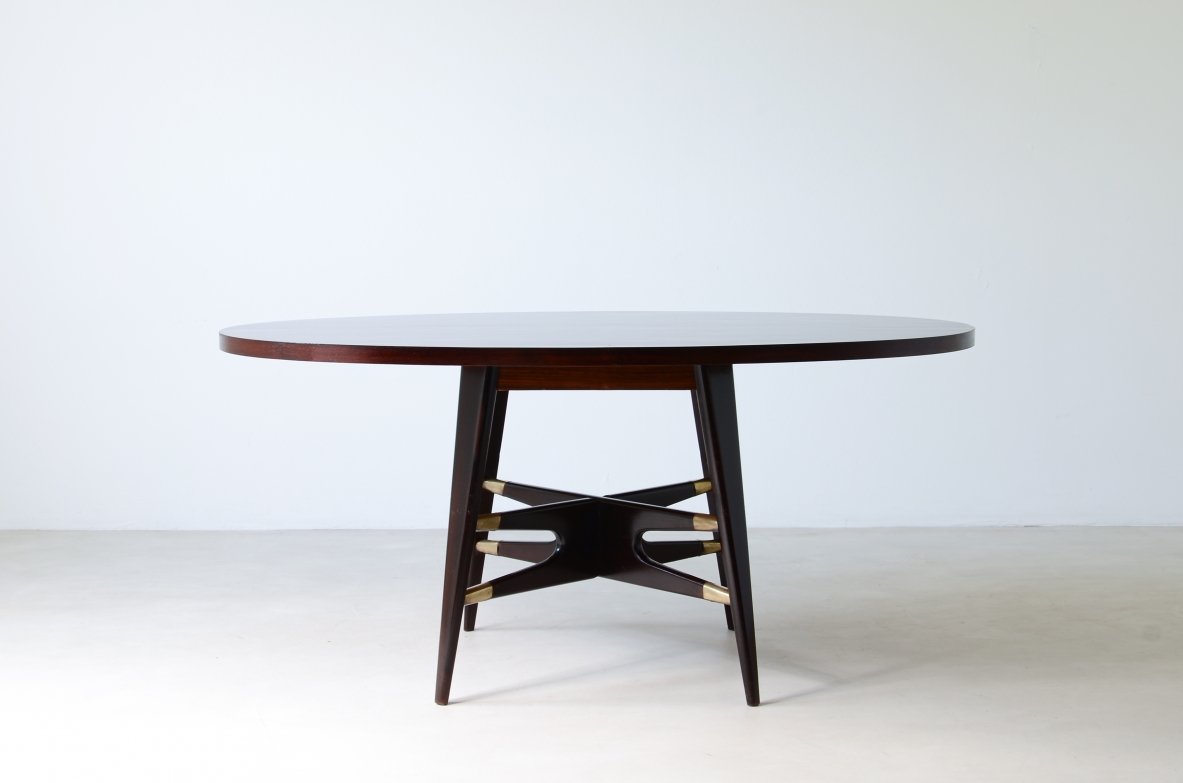Gianni Vigorelli  Elegant oval table in stained wood with four-legged uprights and important cross with brass tips.  Italian manufacture, attr. Vigorelli. 1950 approx.