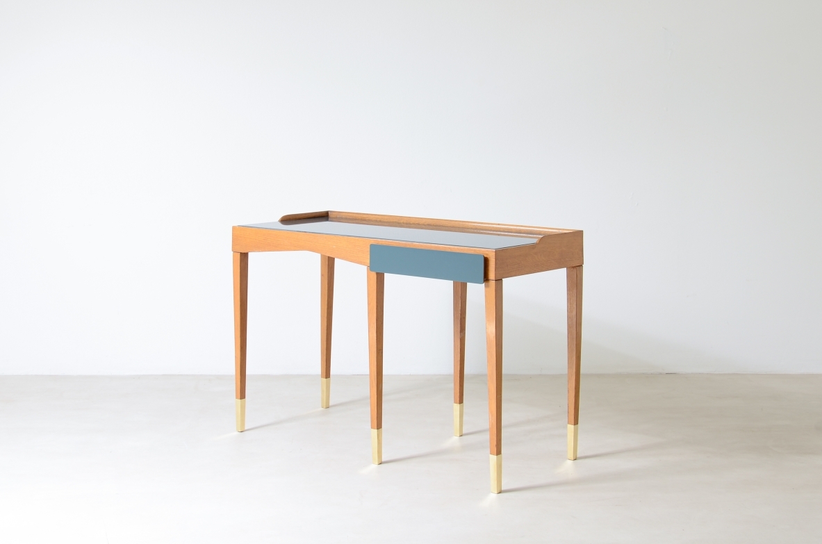 Refined oak writing desk with petrol green opaline glass top and backsplash.  Shaped drawer of the same color covered in polypropylene. Long thin legs with brass tips.  Attributed to Gio Ponti, early 1950s manufacture.