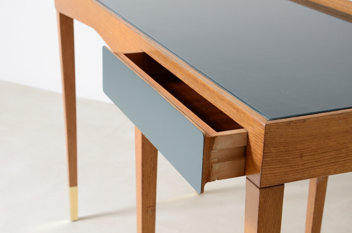 Refined oak writing desk with petrol green opaline glass top and backsplash.  Shaped drawer of the same color covered in polypropylene. Long thin legs with brass tips.  Attributed to Gio Ponti, early 1950s manufacture.