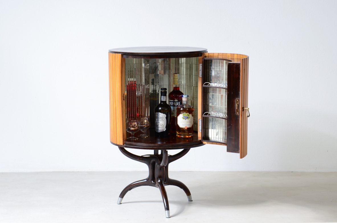 Small bar cabinet in the shape of a column in blond wood with a curved wooden base in the style of Ico Parisi.  Italian manufacture, ca. 1950.