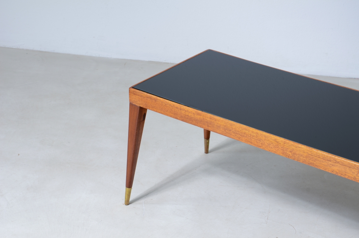 Elegante tavolo basso in mogano chiaro con puntali in ottone e piano in vetro.  Manifattura italiana, 1950ca.