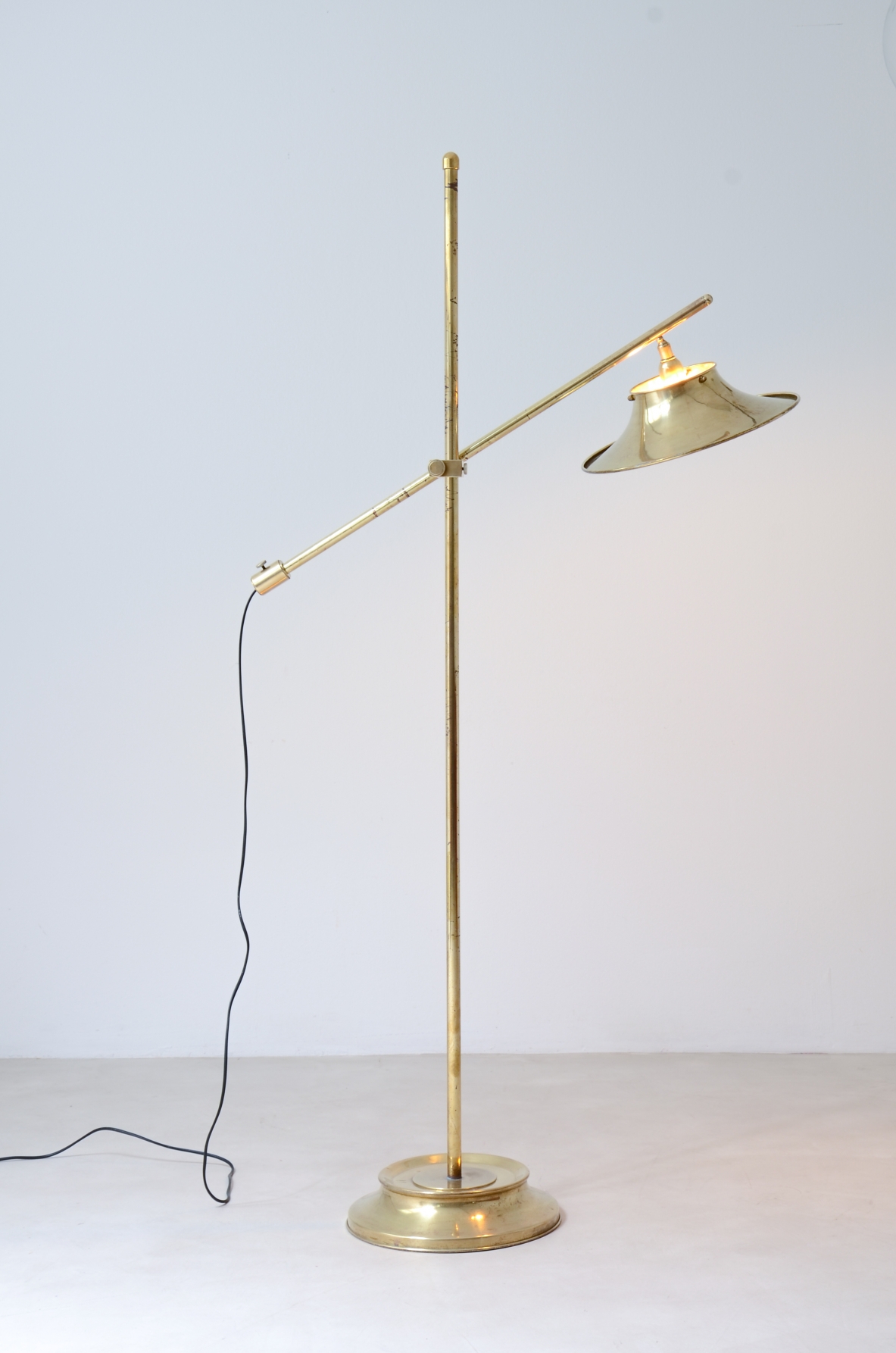 Lampada da terra in ottone con asta a bilanciere, base e cappello in ottone sagomato e forato.  Manifattura italiana, 1950ca.