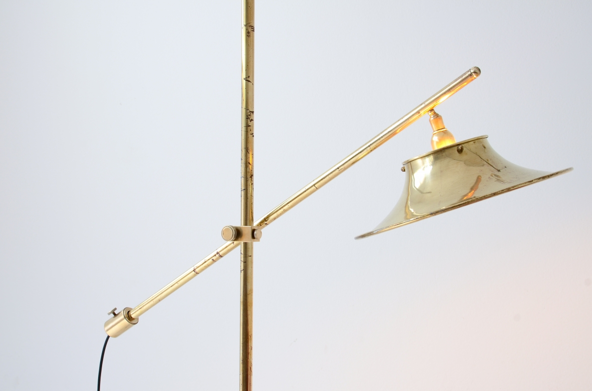 Lampada da terra in ottone con asta a bilanciere, base e cappello in ottone sagomato e forato.  Manifattura italiana, 1950ca.