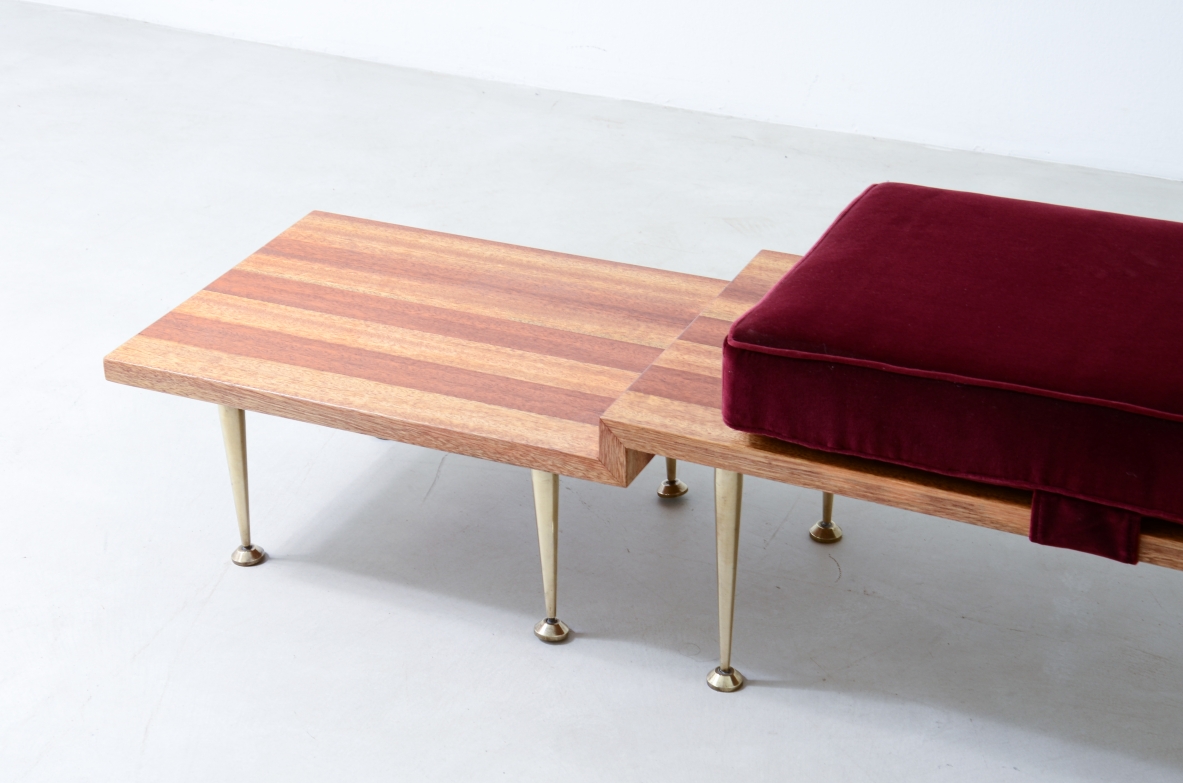 Large shaped wooden bench with eight turned brass feet and velvet-covered cushions.  Italian manufacture from the 1950s