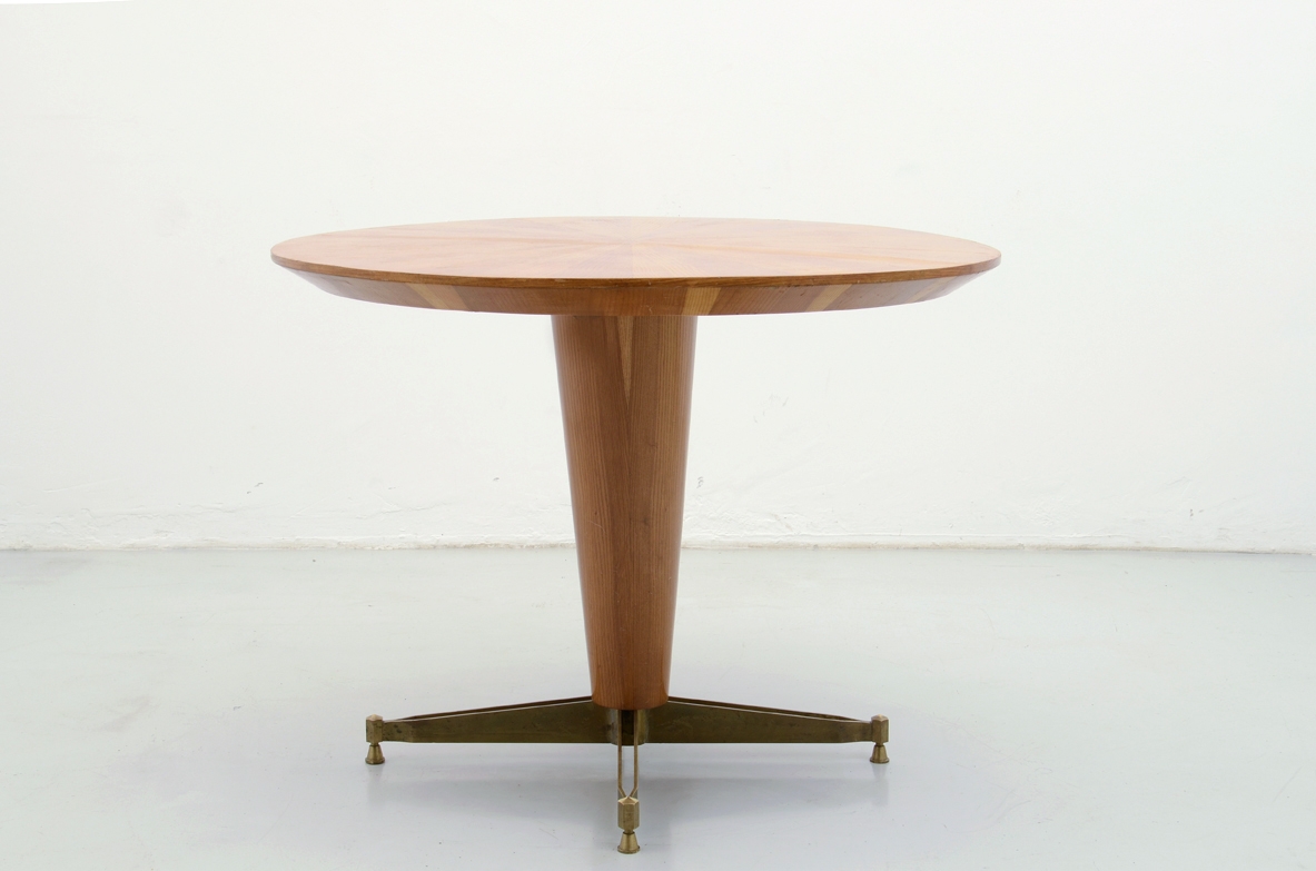 Round dining table in light wood with central column ending with a bronze crossed base, Italy 1950's. Italy, 1950's.